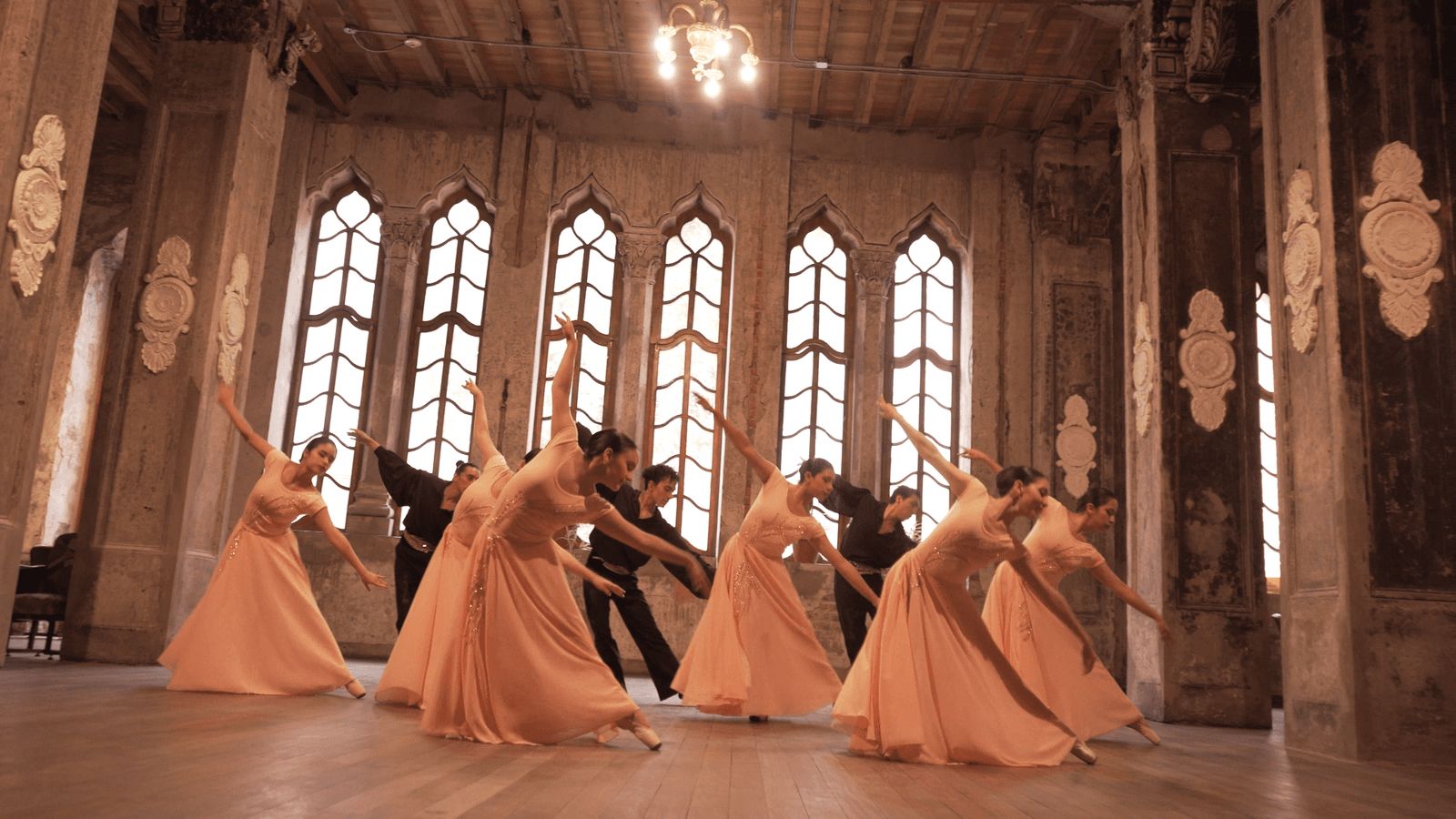 Bailarinas con vestidos largos frente a los ventanales del teatro