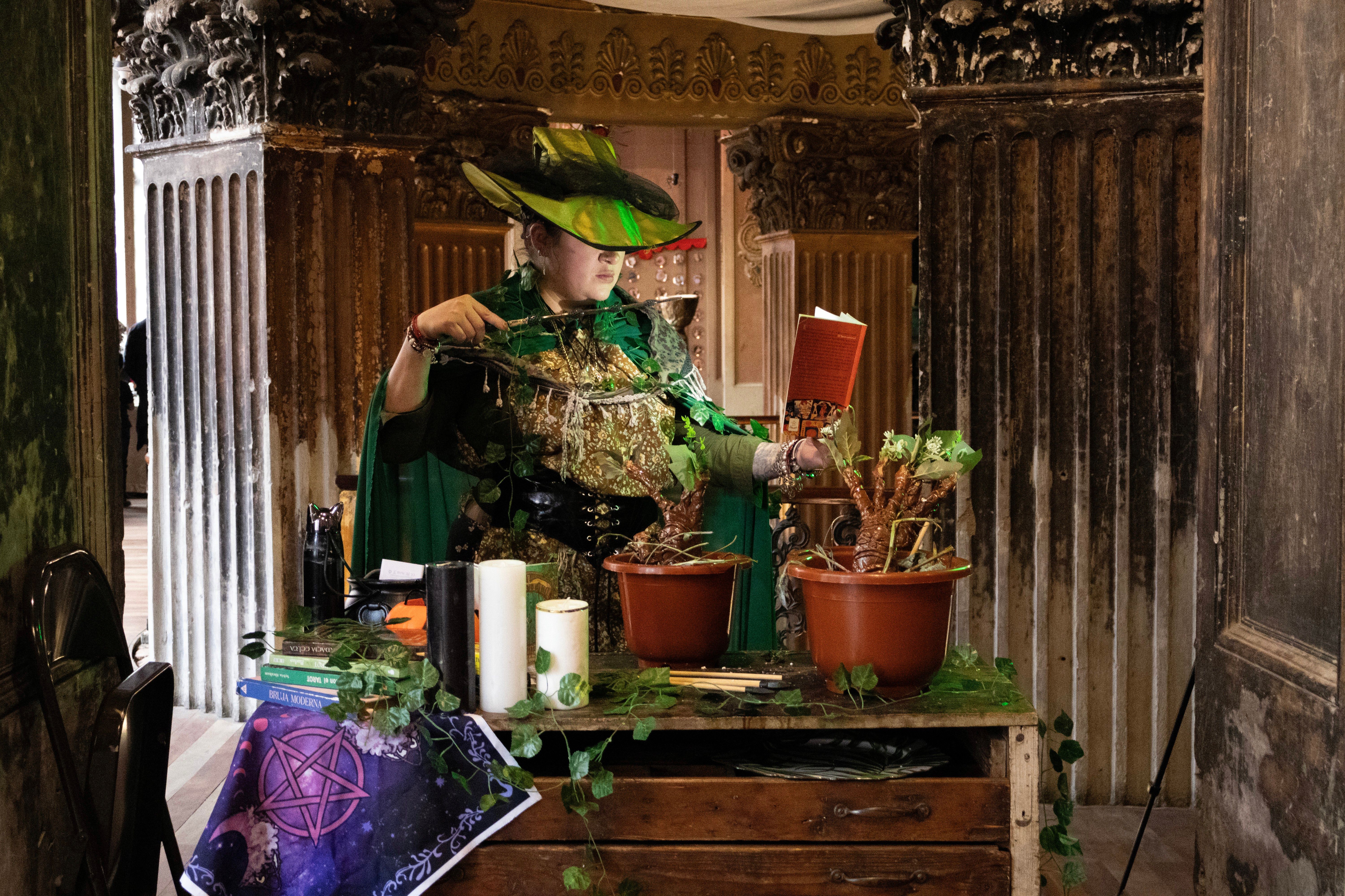 Personaje vestido de verde entre plantas y velas