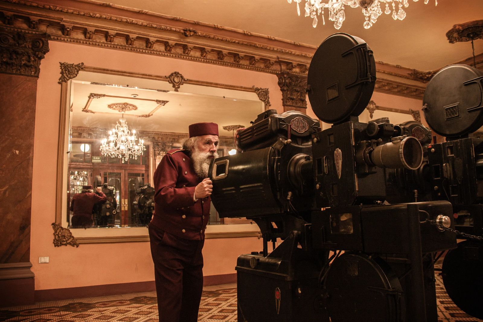 Proyeccionista junto a un antiguo proyector de cine en el teatro